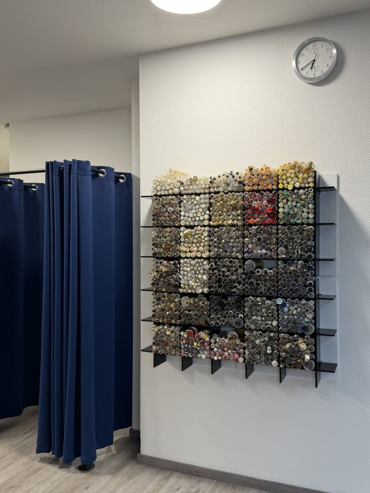 Wand mit hunderten sortierten Knöpfen neben der Umkleidekabine